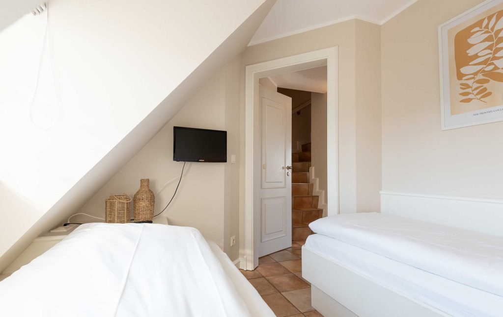 im ersten Schlafzimmer im App. 12 im Haus Carmen in Wenningstedt stehen zwei Einzelbetten und ein TV hängt an der Wand