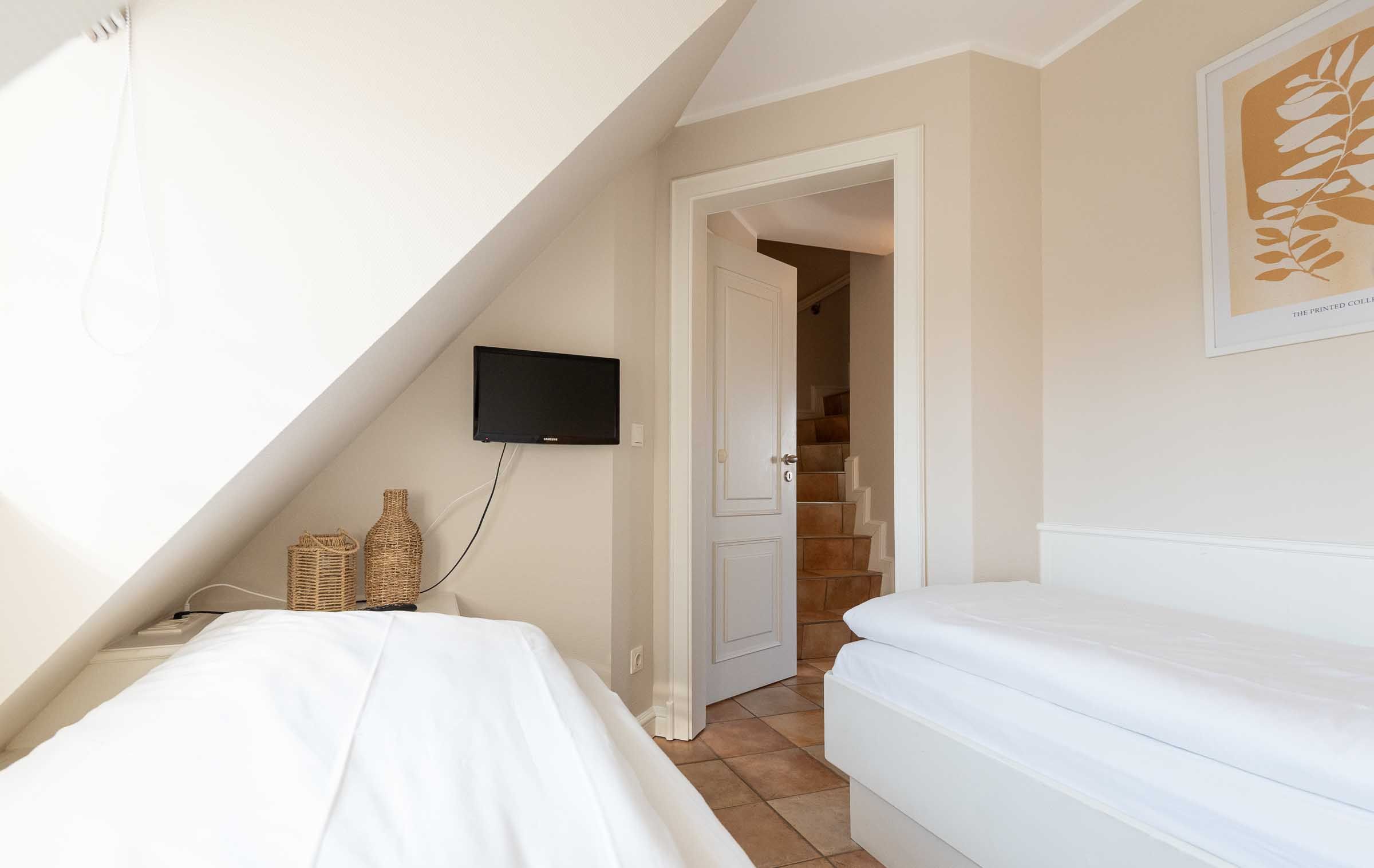 im ersten Schlafzimmer im App. 12 im Haus Carmen in Wenningstedt stehen zwei Einzelbetten und ein TV hängt an der Wand