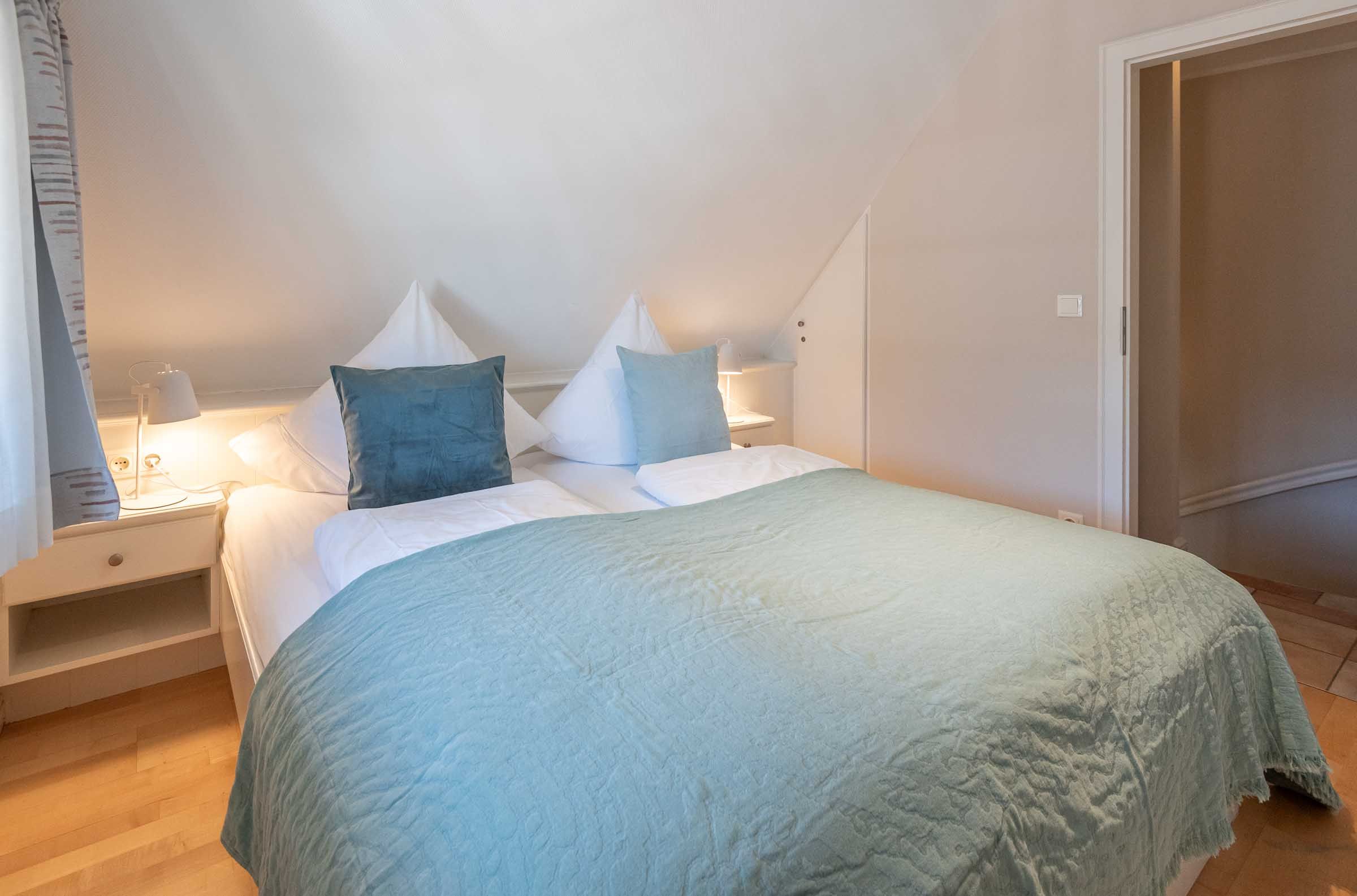 im Schlafzimmer von App. 12 im Haus Carmen steht  ein Doppelbett mit Nachttischen