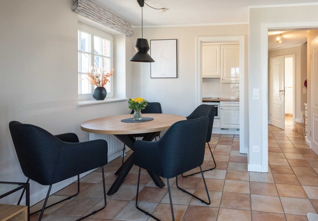 im Wohnzimmer von Ferienwohnung Carmen App. 12 steht ein runder Esstisch mit vier Stühlen