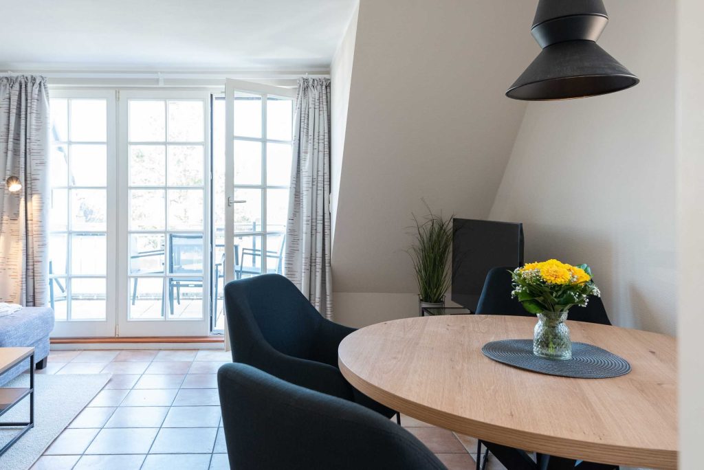 ein runder Esstisch mit vier Stühlen steht im Wohnzimmer der Ferienwohnung Carmen App. 12 in Wenningstedt