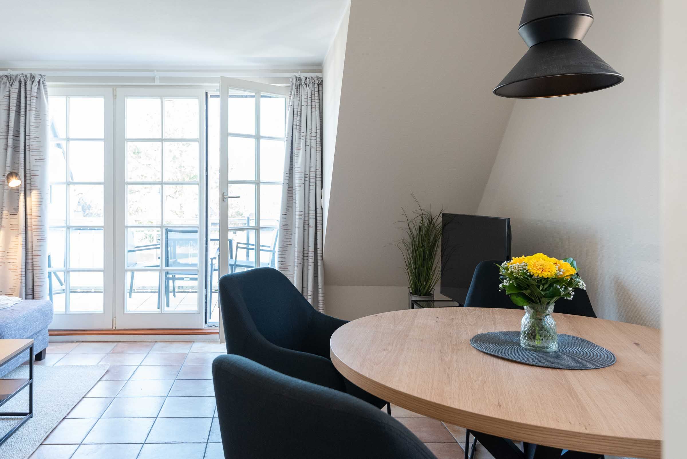 ein runder Esstisch mit vier Stühlen steht im Wohnzimmer der Ferienwohnung Carmen App. 12 in Wenningstedt